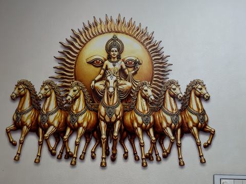 Surya on his chariot with seven horses, printed in gold tones on a white wall